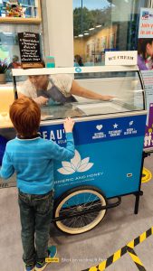 Young boy orders ice cream from ice cream trolley.